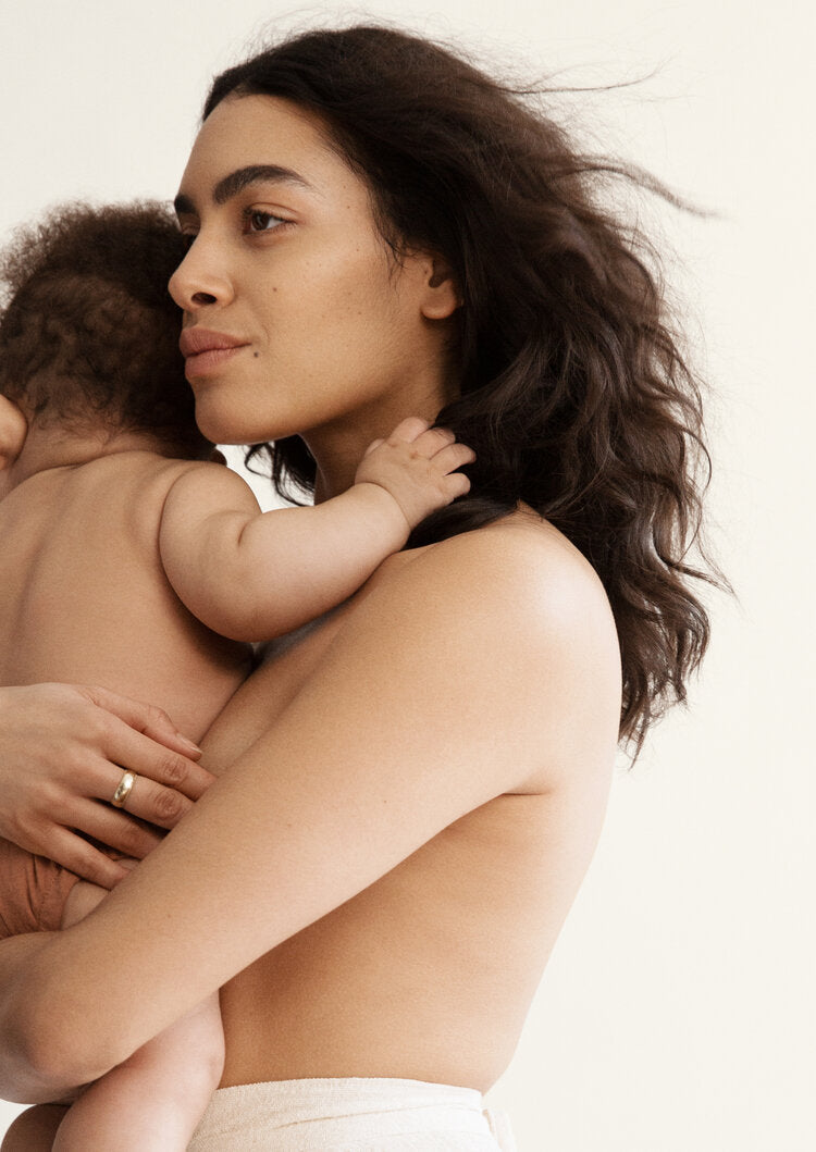 Woman holding a child against a plain background